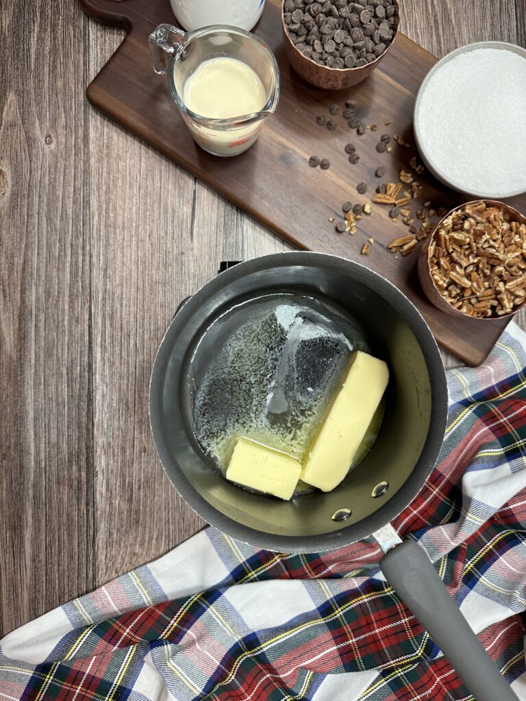 Melting butter in a saucepan next to ingredients for fudge. 