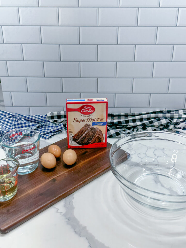 Ingredients for chocolate cake mix on the counter and a glass bowl for mixing