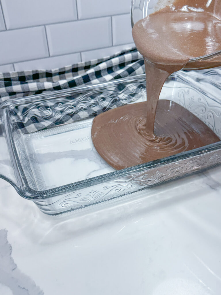 Stirred cake mix being poured into a 13x9-inch baking dish